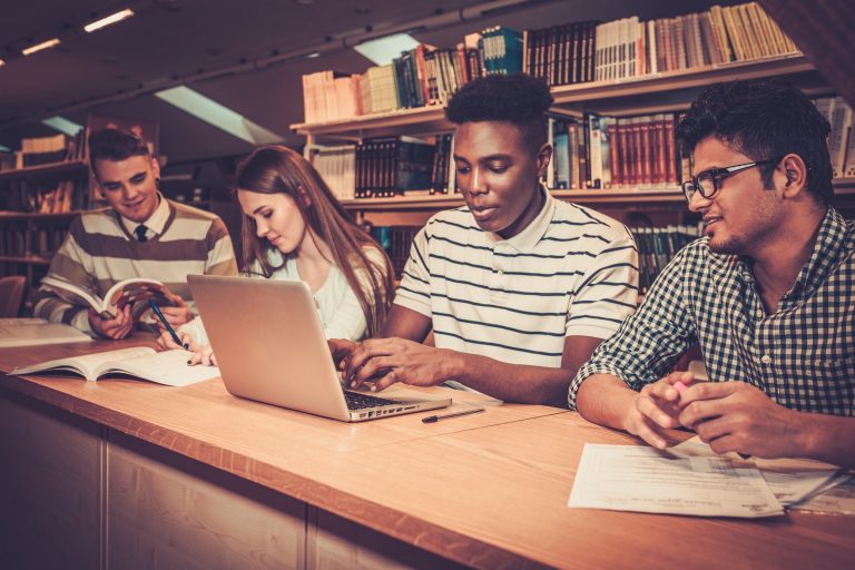 Multinational group of cheerful students studying in the university library.